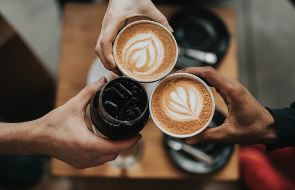 Three people cheering with iced coffee and lattes at Verve Coffee.