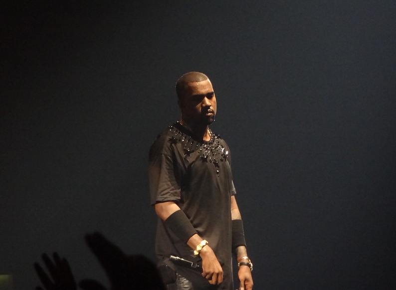 Kanye West performing on stage in a black outfit.