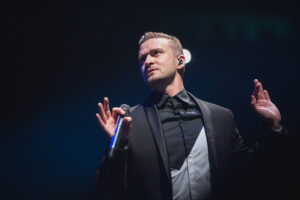 Justin Timberlake on stage at the Canadian Tire Centre in Ottawa, holding a microphone and raising his hands in mid-performance.