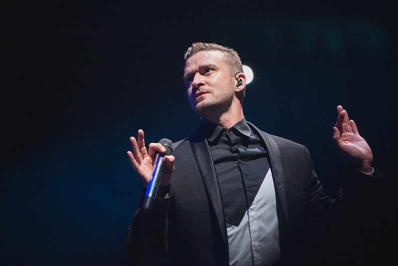 Justin Timberlake on stage at the Canadian Tire Centre in Ottawa, holding a microphone and raising his hands in mid-performance.