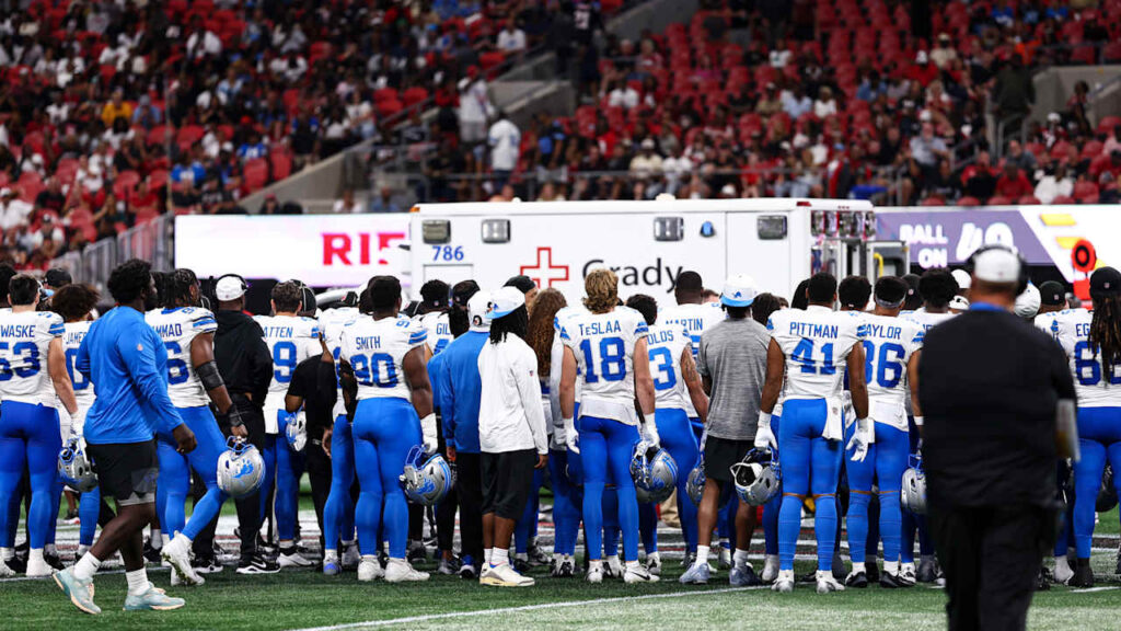 Detroit Lions players stand near an ambulance while medical staff attend to safety Morice Norris in the fourth quarter at Mercedes-Benz Stadium during the Lions–Falcons preseason game.