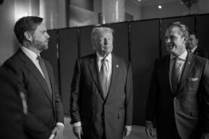 Black and white photograph showing President Donald Trump standing between two men in suits, likely including Defense Secretary Pete Hegseth, all wearing formal attire during what appears to be an official White House event.
