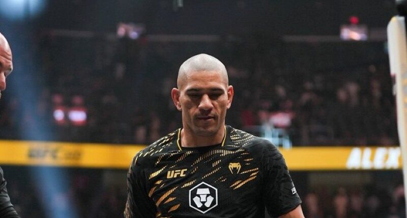 Alex Pereira walking with the UFC Light Heavyweight Championship belt after his victory at UFC 320, wearing black and gold fight shorts and UFC championship gear.