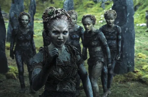 Four mud-covered characters from Game of Thrones sitting together in a forest setting, depicting warriors and supernatural beings united against a common threat.