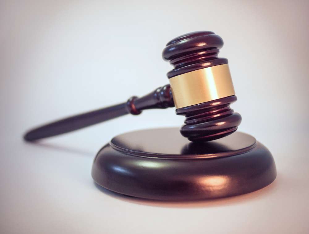 A wooden gavel, symbolizing judicial authority, resting on a sound block.
