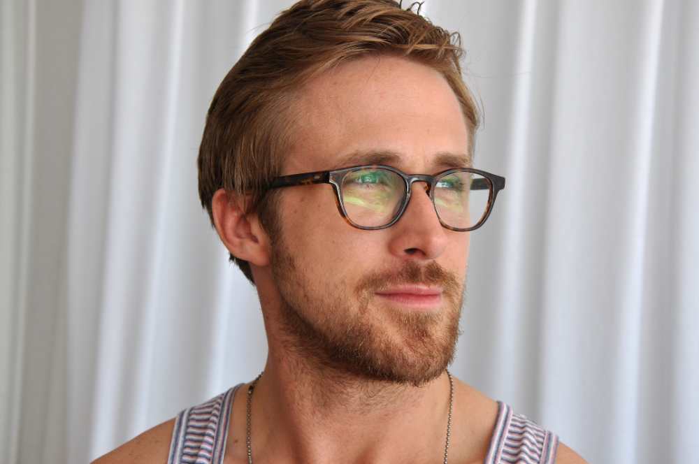 Ryan Gosling at the 2011 Cannes Film Festival, wearing a dark suit, glasses, and a beard, smiling slightly.