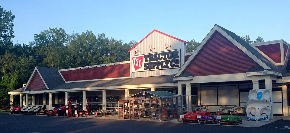 Exterior view of Tractor Supply Company store in Farmington, Connecticut with red metal roof, tan/brown walls, portico entrance, and prominent company signage.