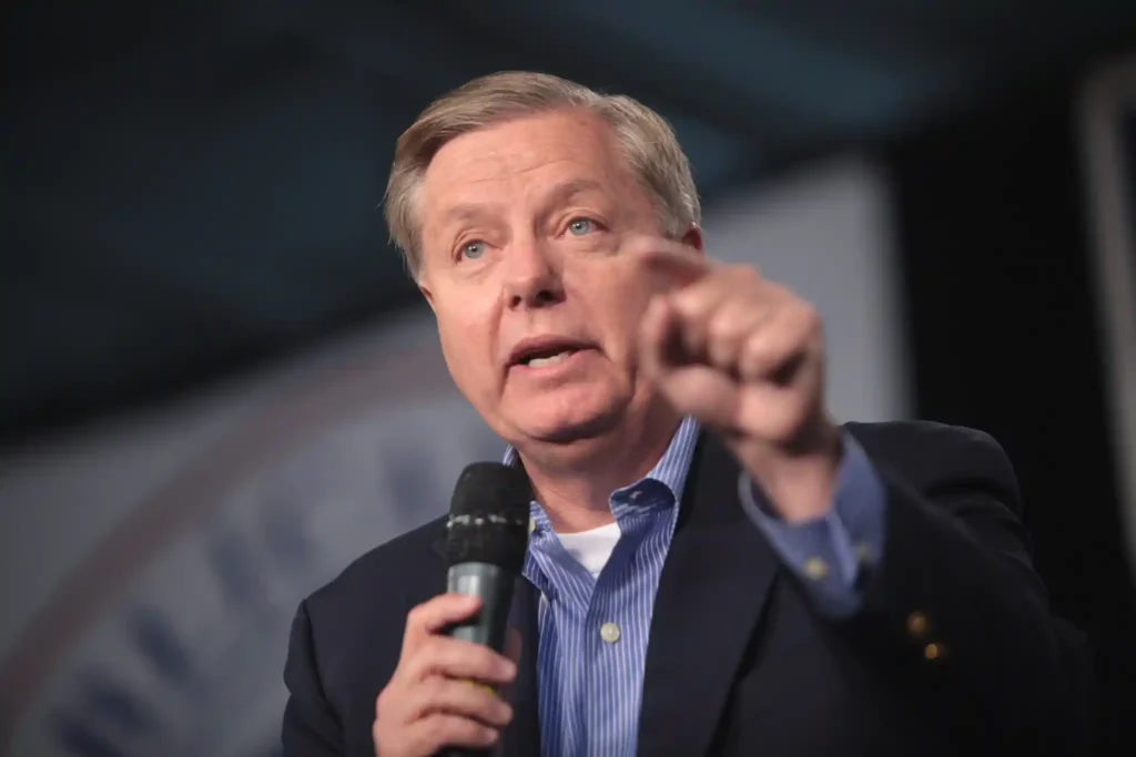 U.S. Senator Lindsey Graham speaking into a handheld microphone while addressing an audience during a public event in Des Moines, Iowa, in October 2015.
