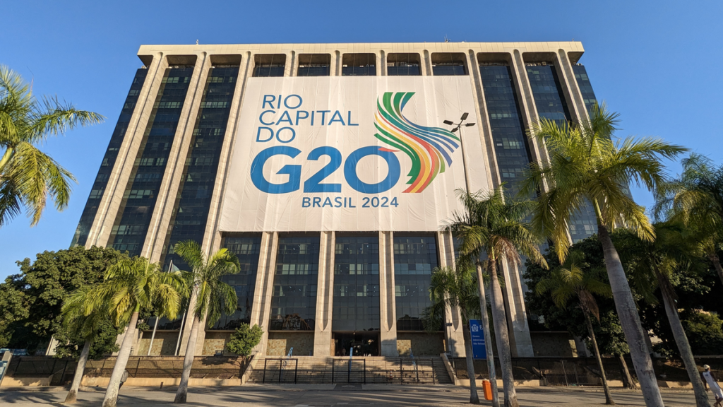 Large G20 Brasil 2024 banner on administrative building in Rio de Janeiro with palm trees and blue sky