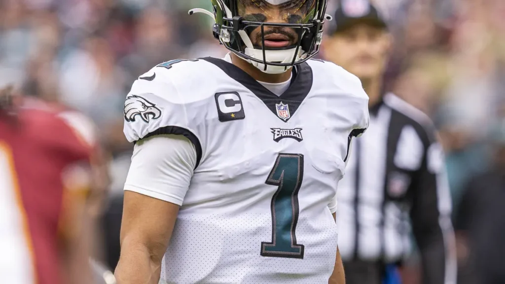 Philadelphia Eagles quarterback Jalen Hurts in green uniform preparing for a snap during an NFL game.
