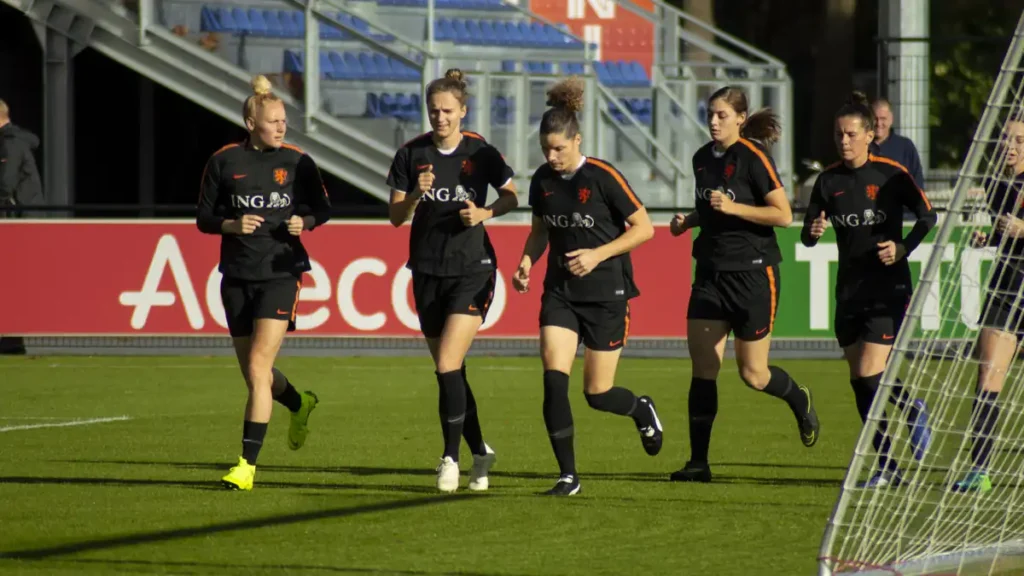 Netherlands women's national football team players training on a grass pitch