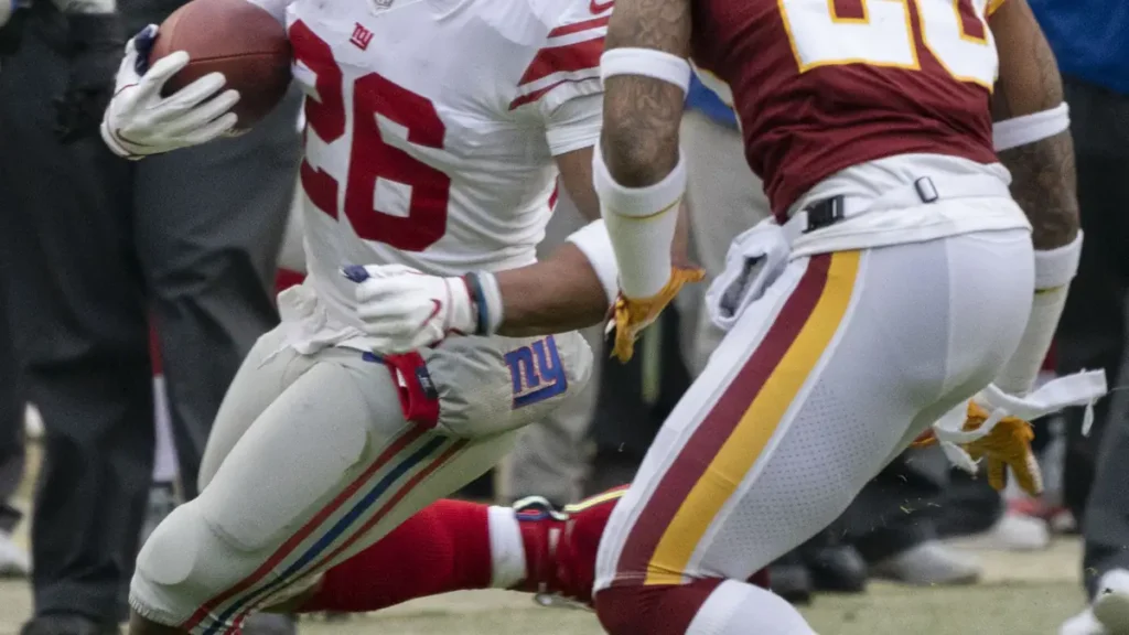 NFL running back Saquon Barkley running with the football during a game.